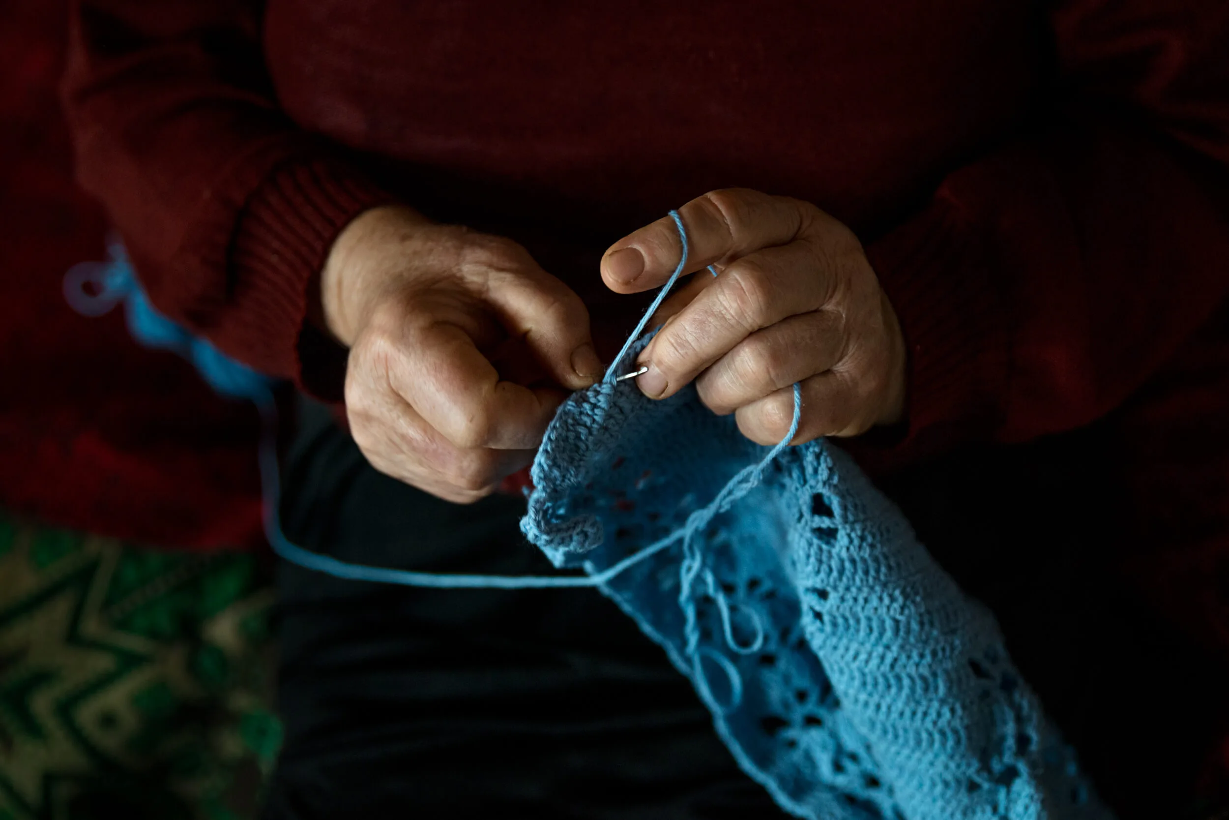 Ръце на баба плетат синьо вълнено изделие